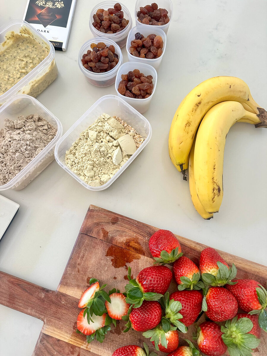 Bananas, strawberries, overnight oats and protein powder laid out on a bench