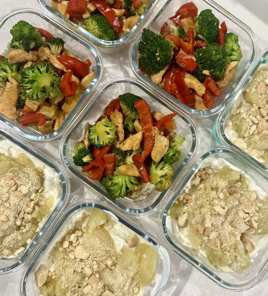 Glass containers of prepped chicken, broccoli and capsicum stir fry with yoghurt and fruit pots